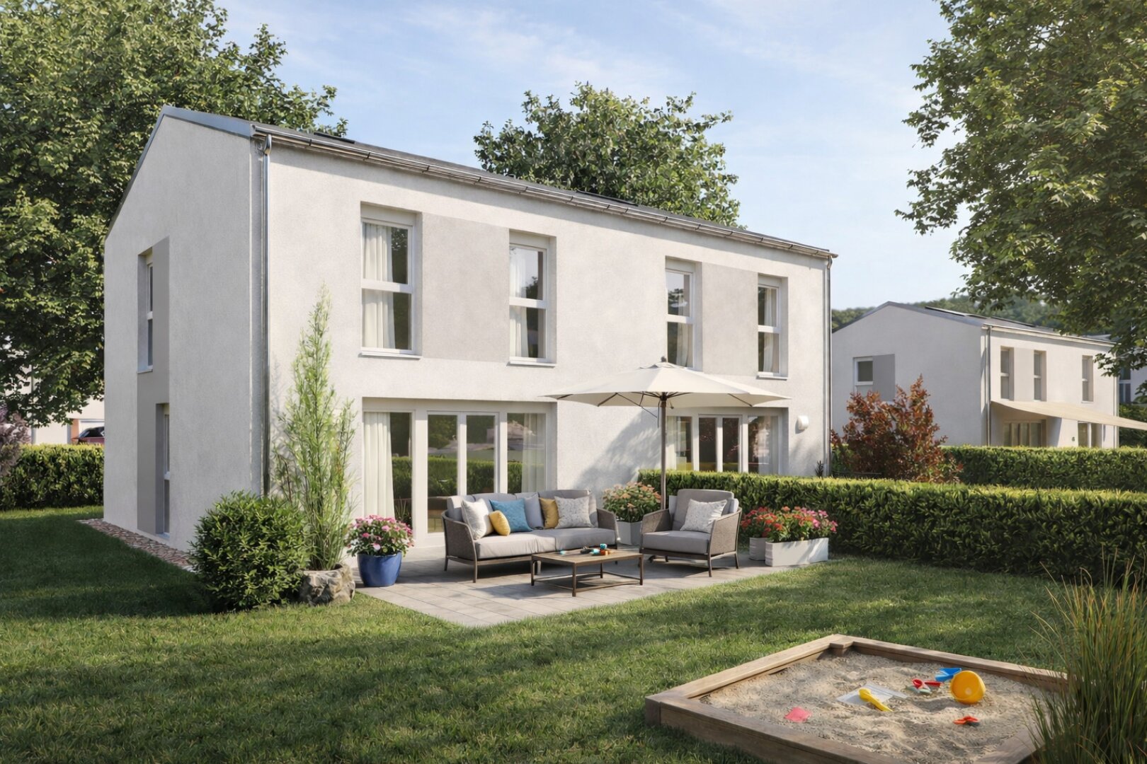Ein modernes zweistöckiges weißes Haus mit großen Fenstern, einer Terrasse mit Gartenmöbeln und einem Sonnenschirm, umgeben von Grünflächen. Im Vordergrund befindet sich ein Sandkasten mit Kinderspielzeug auf einem grasbewachsenen Rasen.