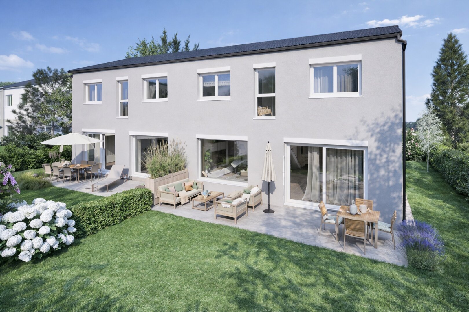 Ein modernes zweistöckiges Haus mit großen Fenstern und einer geräumigen Terrasse mit Sitzgelegenheiten im Freien, Tischen, Sonnenschirmen und einem gepflegten grünen Rasen, der an sonnigen Tagen von Büschen und Bäumen umgeben ist.